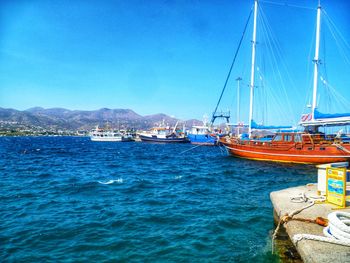 Sailboats moored in sea against clear blue sky