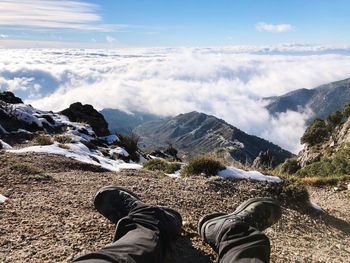 Low section of person on mountains against sky