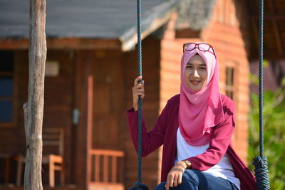 Portrait of young woman swinging on sunny day