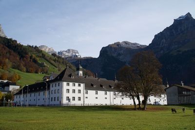 Houses on field by mountains against sky