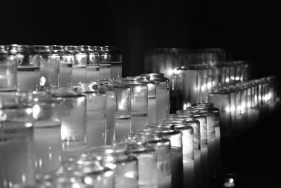 Illuminated tea light candles on shelf at night