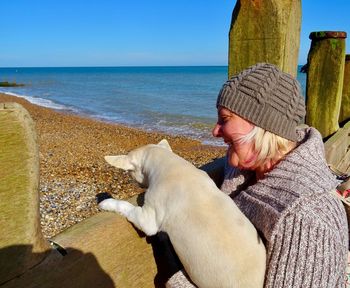 Close-up of woman with dog rearing on railing at beach