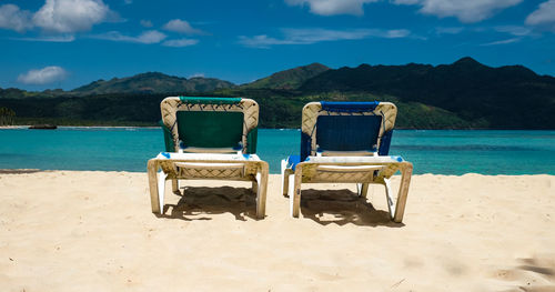 Chairs on beach against sky