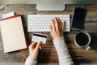 Top view on female hands on a computer keyboard holding credit card. businesswoman in the office.