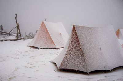 Tents on snow covered field against sky