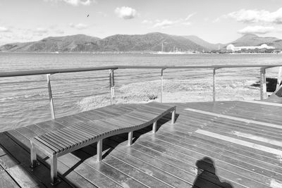 Empty chairs by sea against sky