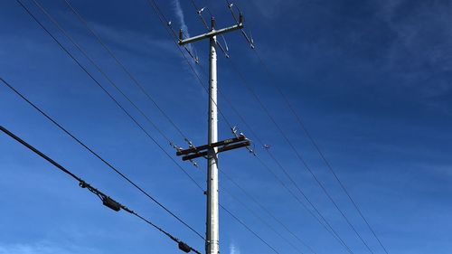 Low angle view of electricity pylon against blue sky