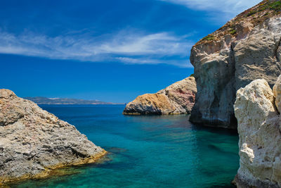 Rock formations by sea against blue sky