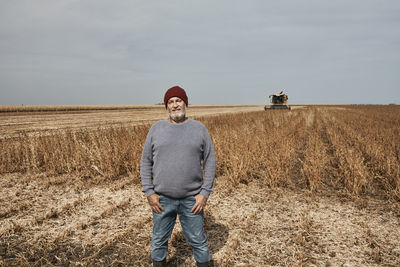 Smiling farmer standing with hands in pockets at soybean farm