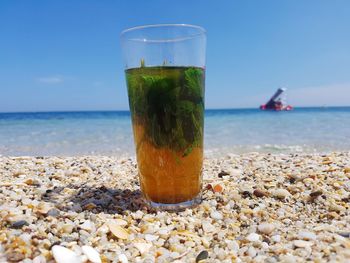 Drink on rock by sea against sky