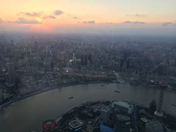 High angle view of city by river against sky during sunset