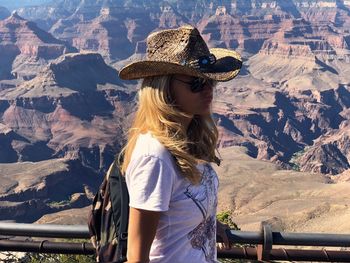 Woman wearing hat standing against mountains
