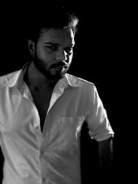 Young man looking away against black background