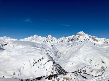 Scenic view of snowcapped mountains against blue sky