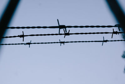 Low angle view of silhouette barbed wire against clear sky