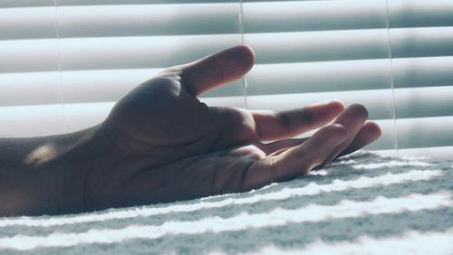 Cropped image of hand relaxing on bed