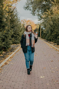 Portrait of young woman standing on footpath