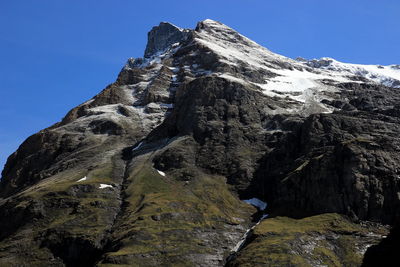 Rocky hiking path with patches of snow during late spring in the swiss alps.