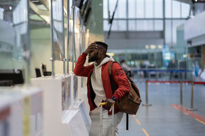 Upset african student guy in airport feeling uncertain about moving to another country