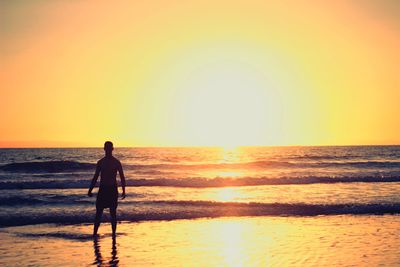 Man standing by sea against sky during sunset