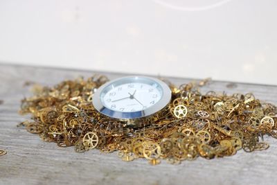 Close-up of clock watch and clockwork cogs on table