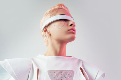 Portrait of young woman standing against white background