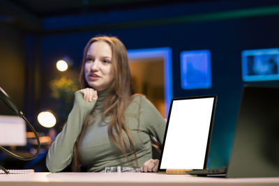 Portrait of young woman using laptop at office