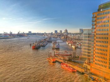 High angle view of city buildings by river against sky