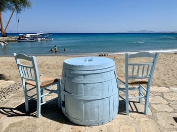 Chairs on beach by sea against clear sky