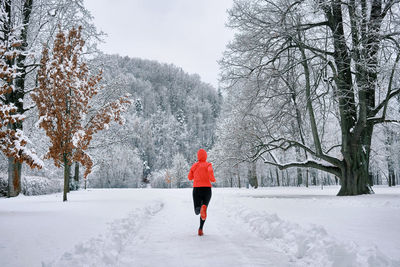 Rear view of woman walking on snow covered landscape