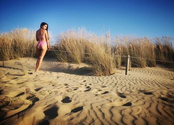 Woman standing on beach against clear sky