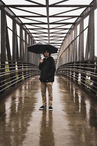 Full length of man standing on wet footbridge