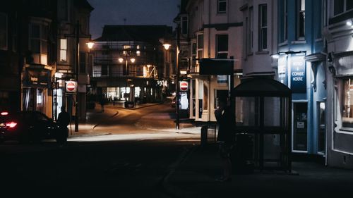 Illuminated street amidst buildings in city at night