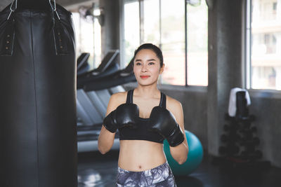 Smiling woman with boxing gloves standing at gym