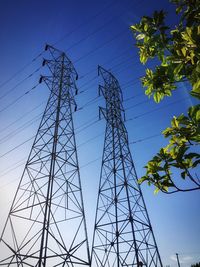 Low angle view of electricity pylon against clear blue sky