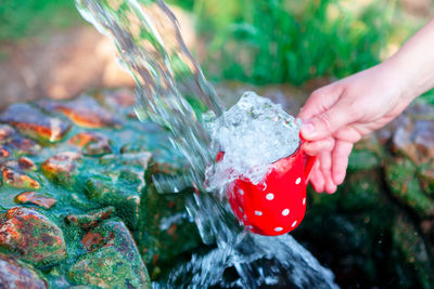 Spring water flows into a cup . hand holding mug with freshwater