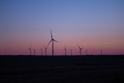 Wind turbines in a field at sunset in a rural.