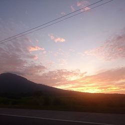 Scenic view of mountains against cloudy sky at sunset