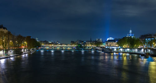 Illuminated bridge over river in city at night