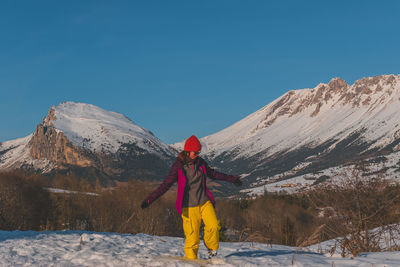 A full-body shot of a young caucasian woman walking towards the camera in the french alps mountains