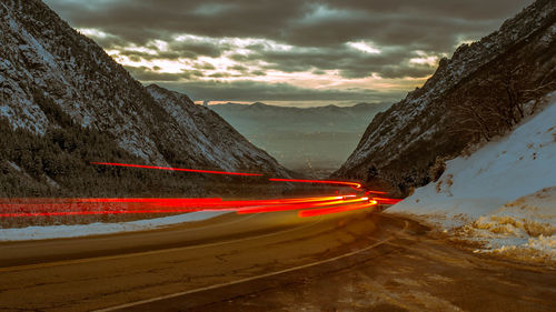 Light trails on road amidst mountains at dusk