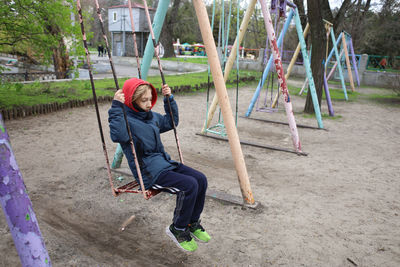 Rear view of people sitting on swing in playground