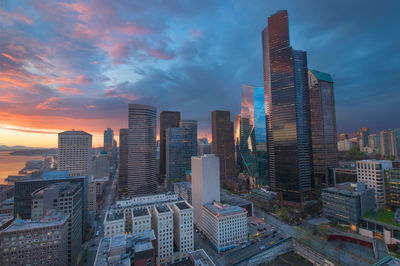 Modern buildings in city against sky during sunset