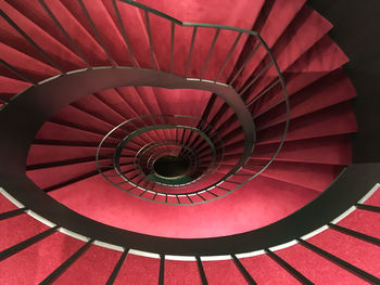 Directly above shot of empty red spiral staircase in building