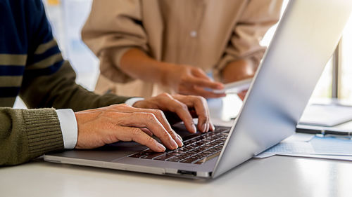 Midsection of man using laptop on table