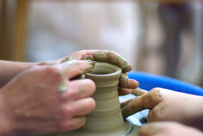 Cropped hands of people making clay pot