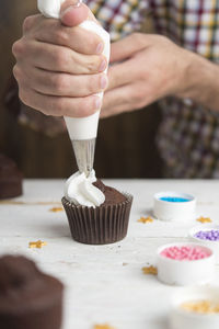 Cropped image of hand holding ice cream on table