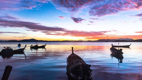 Silhouette boats in sea against sky during sunset