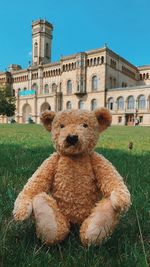 Stuffed toy on field against clear blue sky