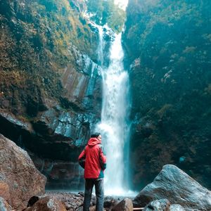 Rear view of man standing by waterfall